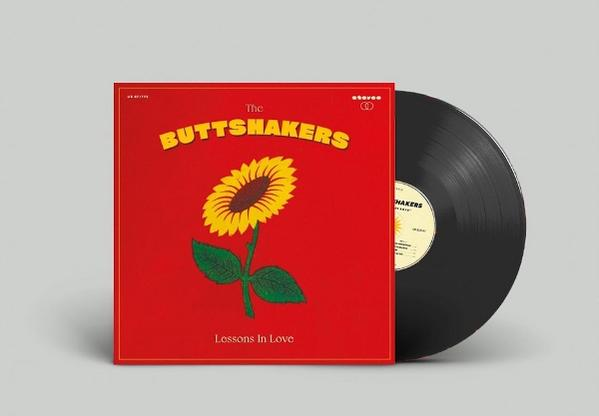 Albumcover von The Buttshakers, ein rotes Quadrat mit Sonnenblume und Schallplatte. Die Schallplatte ist schwarz. Titel: Lessons In Love.