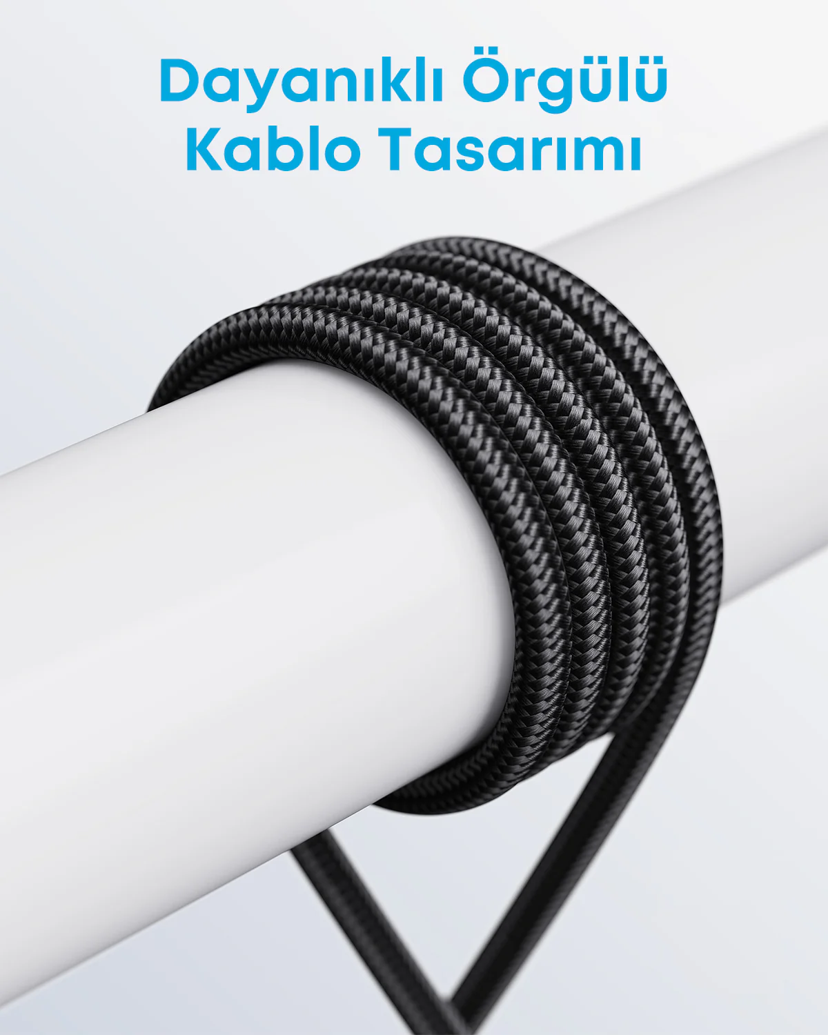Siyah örgülü bir kablonun beyaz silindirik bir nesneye sarılmış yakın çekimi. Kablo dokulu bir yüzeye sahip.