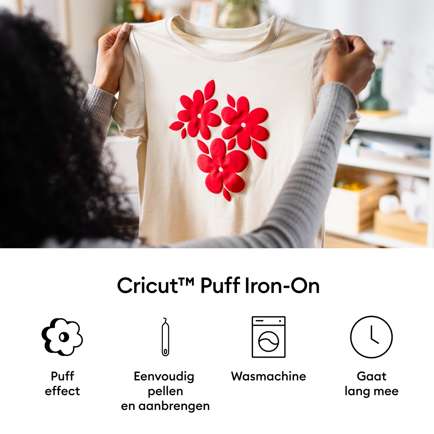 A person holding a beige t-shirt decorated with red flower shapes. The shirt is part of a Cricut Puff Iron-On promotion.