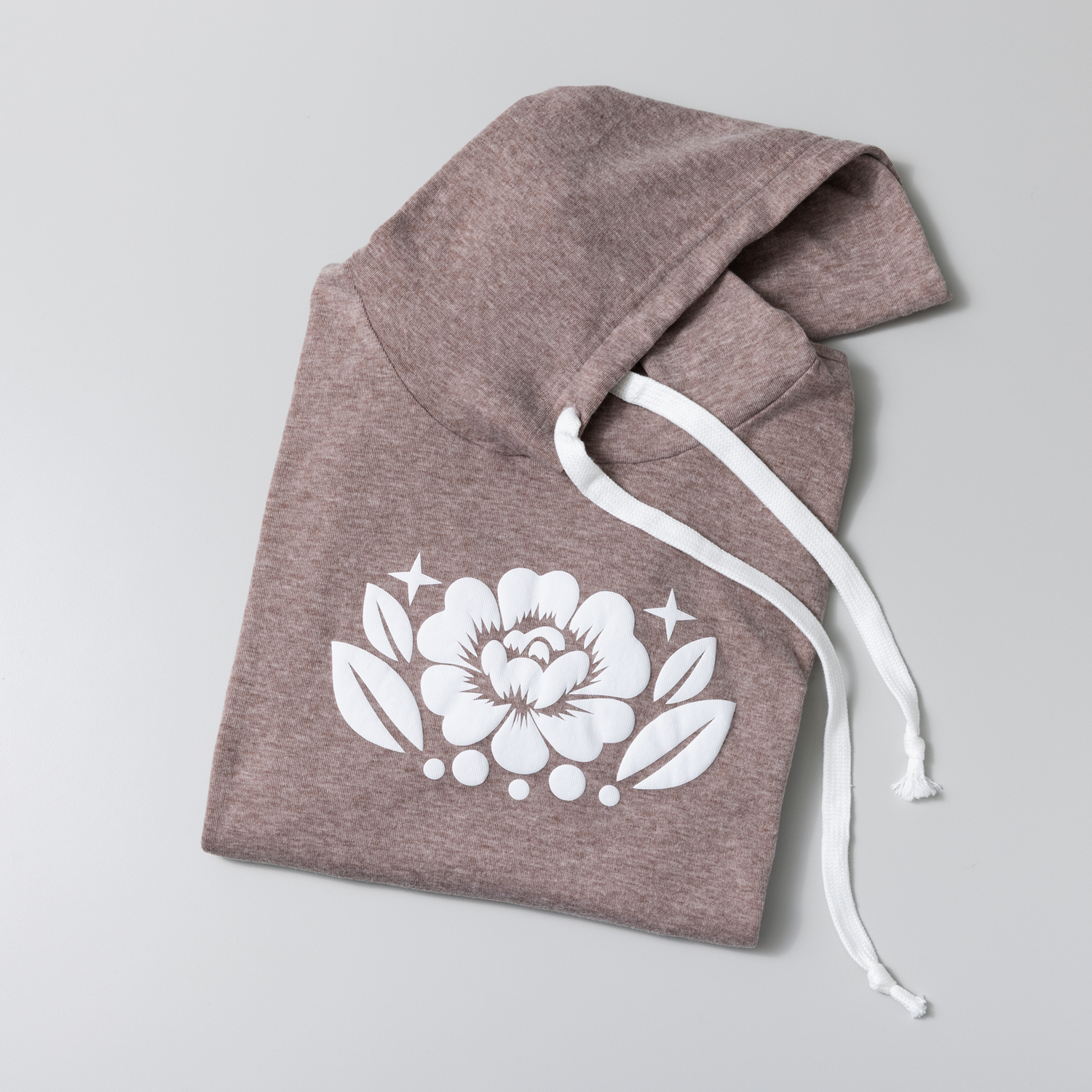 A brown hoodie with a white floral design. The hood is up, and white drawstrings are visible. The background is light gray.