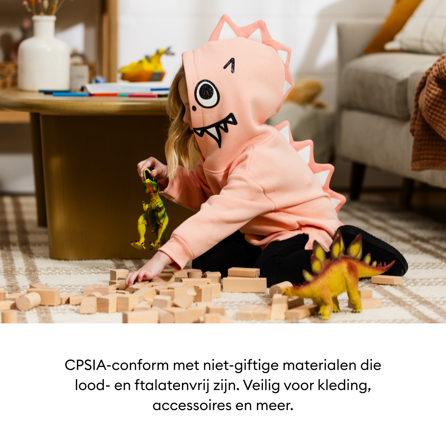 A child in a dinosaur hoodie plays with toy dinosaurs and wooden blocks on a rug near a table and sofa.