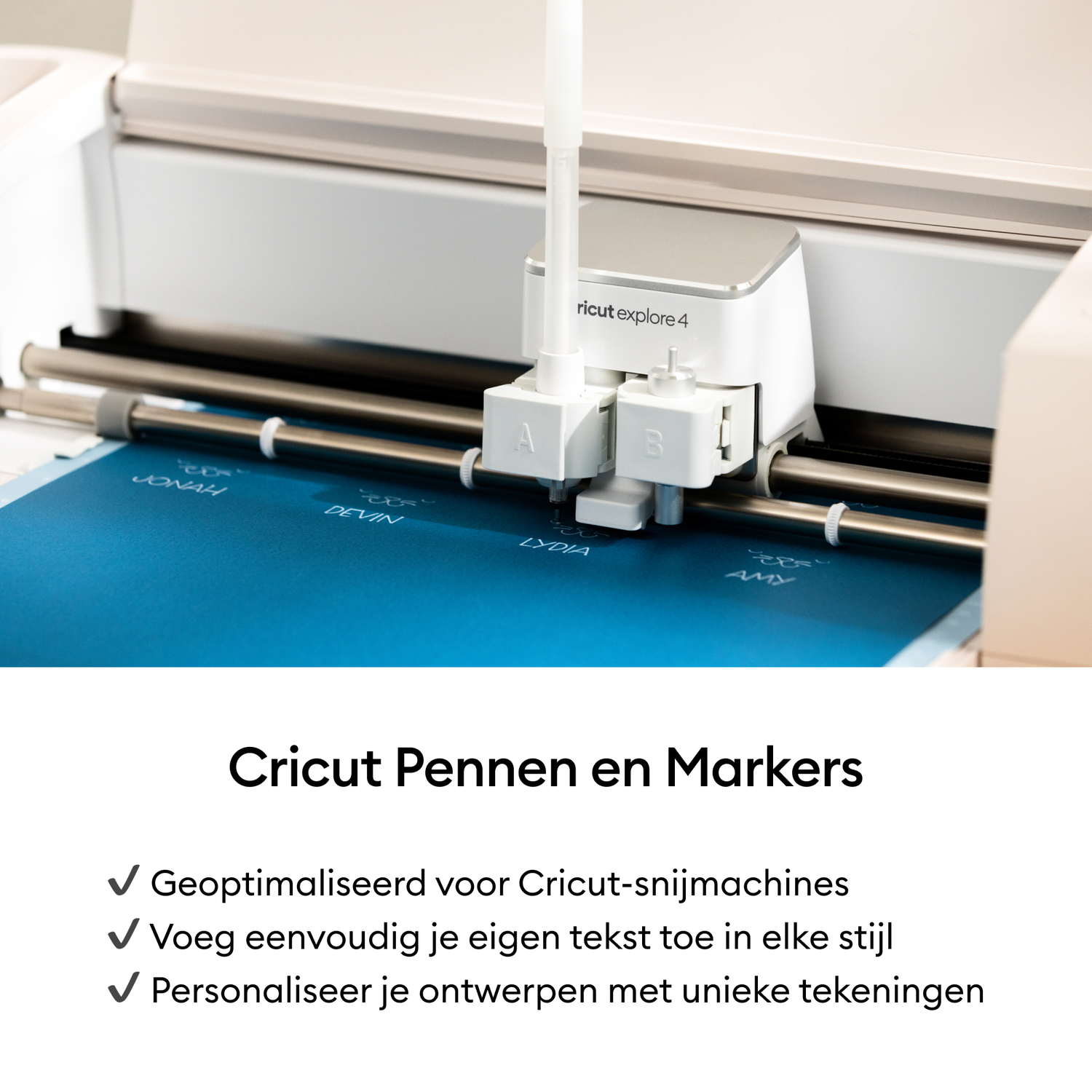 A Cricut Explore 4 machine with a pen is cutting names on blue material. The machine is white and silver.
