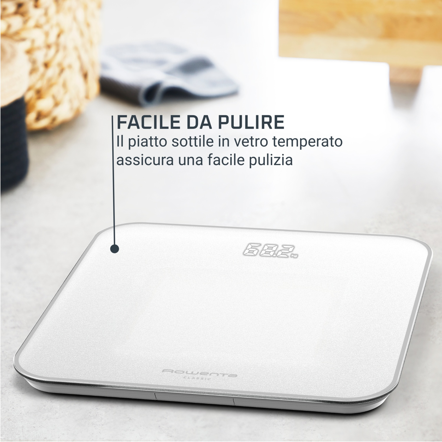 Una bilancia digitale bianca e argento mostra 68,2 kg. La bilancia è su una superficie bianca con un cestino e un panno sullo sfondo.