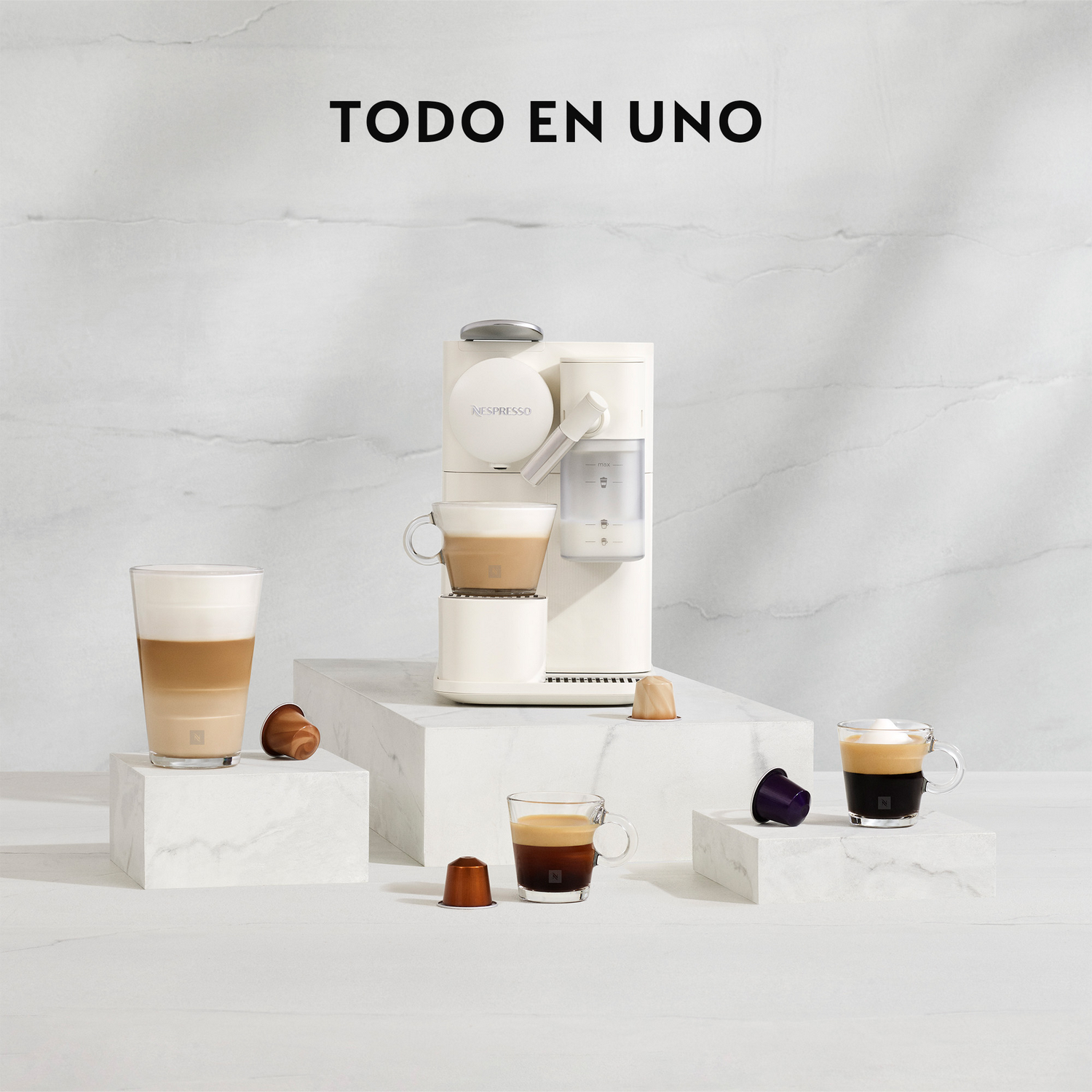 Una máquina Nespresso blanca con tazas de café y cápsulas sobre plataformas de mármol. El texto 'TODO EN UNO' está en la parte superior.