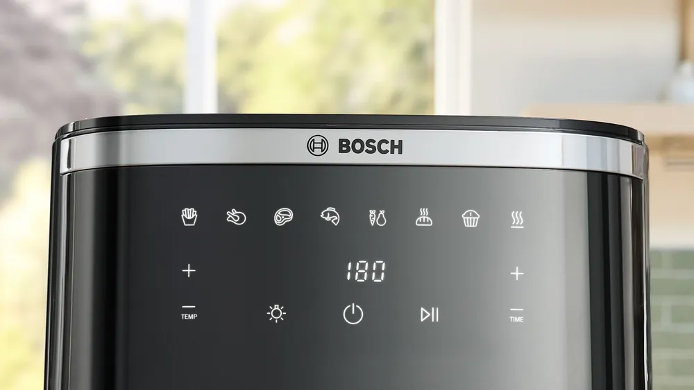 Közelkép egy fekete Bosch légkeveréses sütő vezérlőpaneljéről ikonokkal, a 180-at mutató digitális kijelzővel és a Bosch logóval.