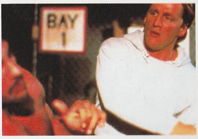Ein Mann im weißen Hemd zeigt mit dem Finger. Im Hintergrund ist ein Schild mit der Aufschrift 'BAY 1' zu sehen.