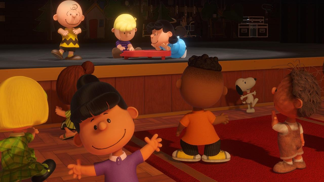 Cartoon-Kinder auf einer Bühne. Charlie Brown, Lucy und Snoopy sind zu sehen. Die Bühne hat einen roten Teppich und Holzverkleidung.
