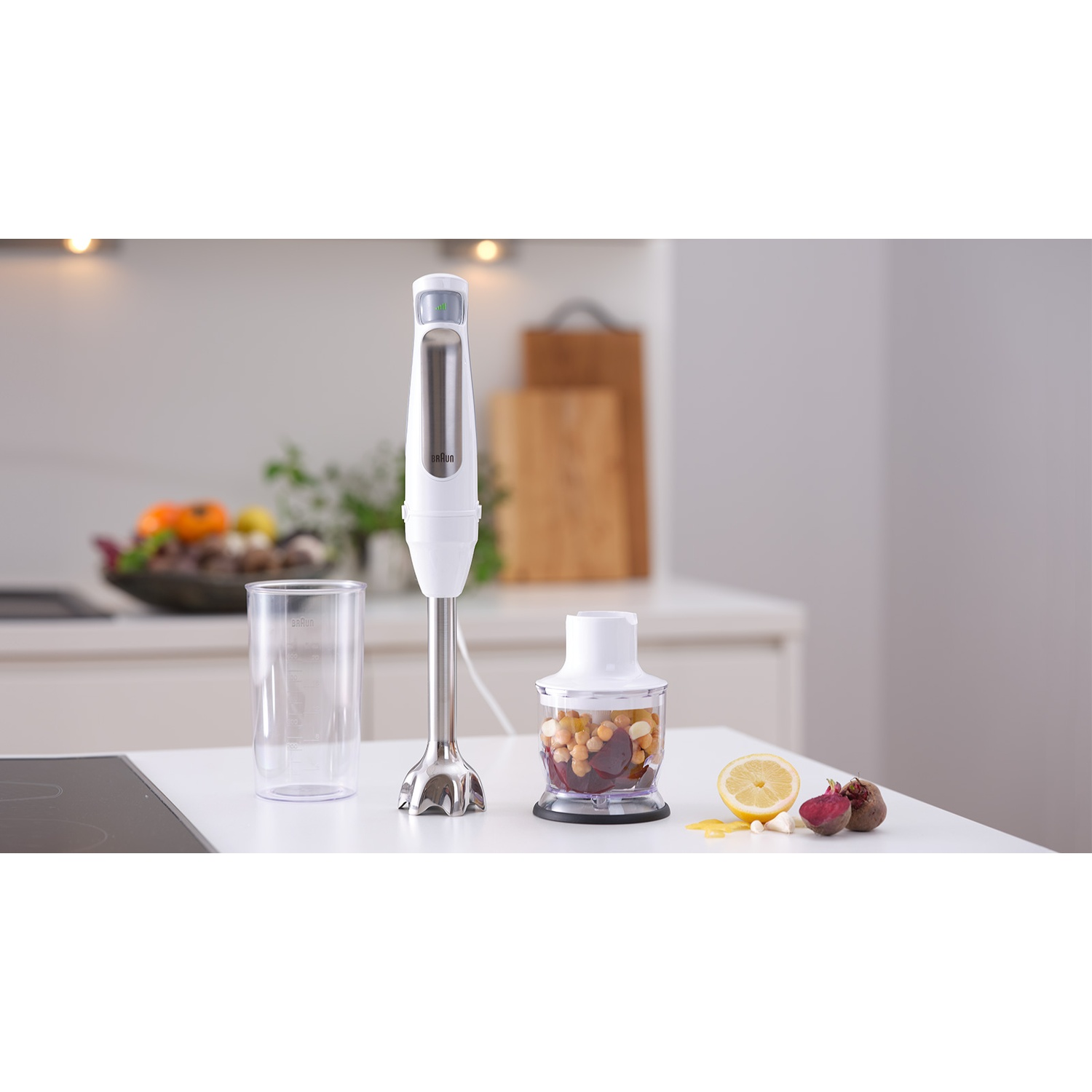 Een witte staafmixer op een aanrecht. Daarnaast een bakje met kikkererwten, bieten, citroen en knoflook.