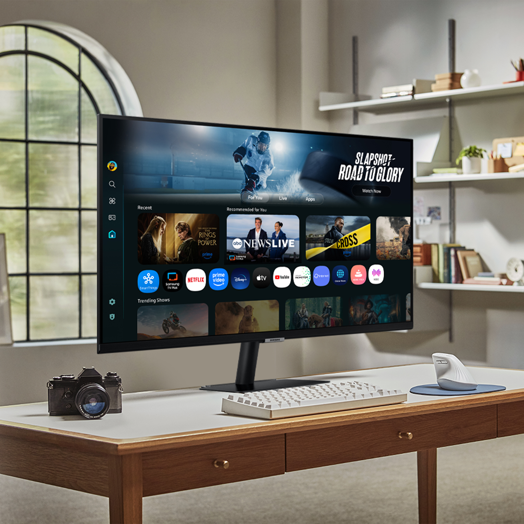 Moderner Schreibtisch mit Monitor, Tastatur, Maus und Kamera. Der Monitor zeigt eine Streaming-Oberfläche.
