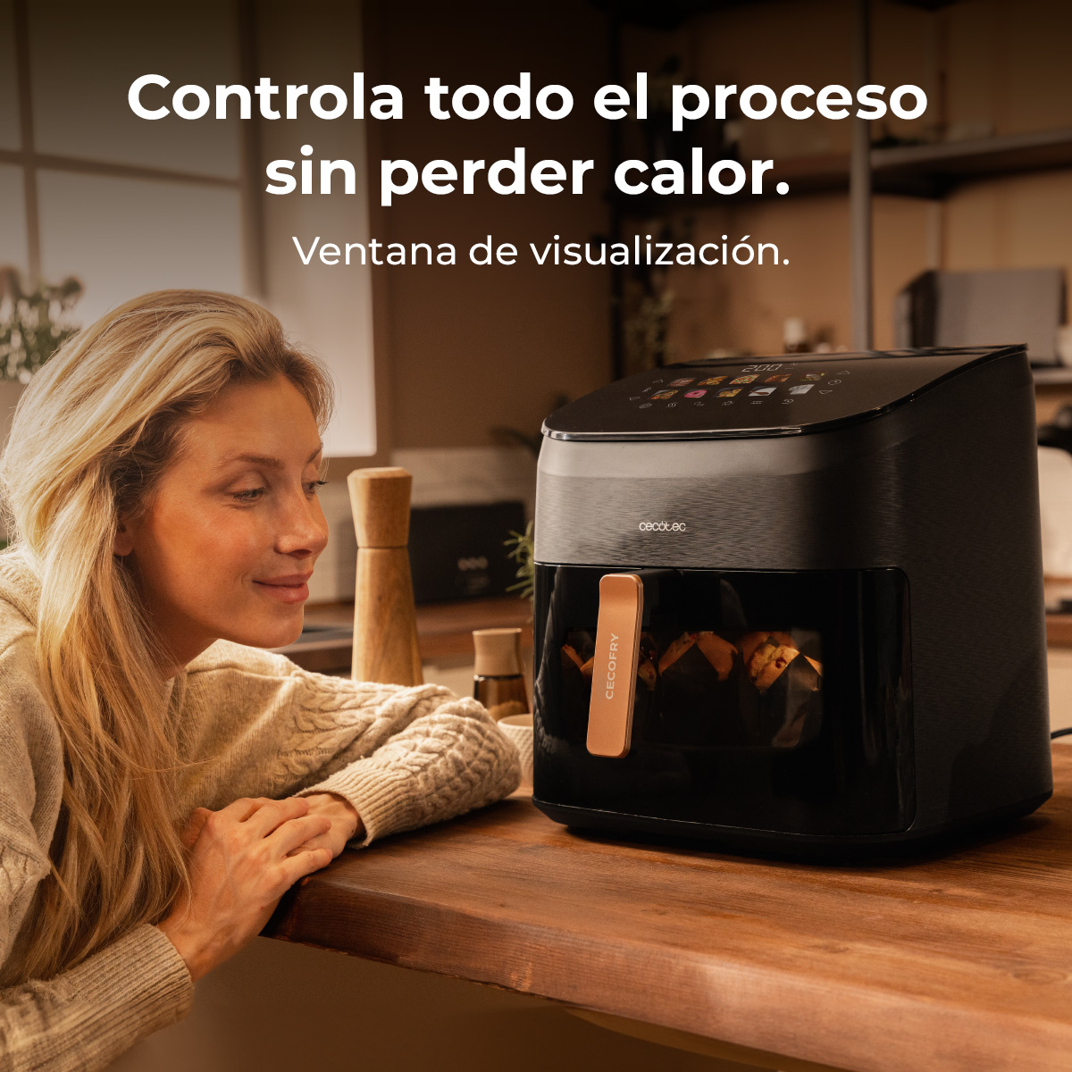 Mujer mira una freidora de aire Cecotec negra sobre una encimera de madera. Texto: Controla todo el proceso sin perder calor.