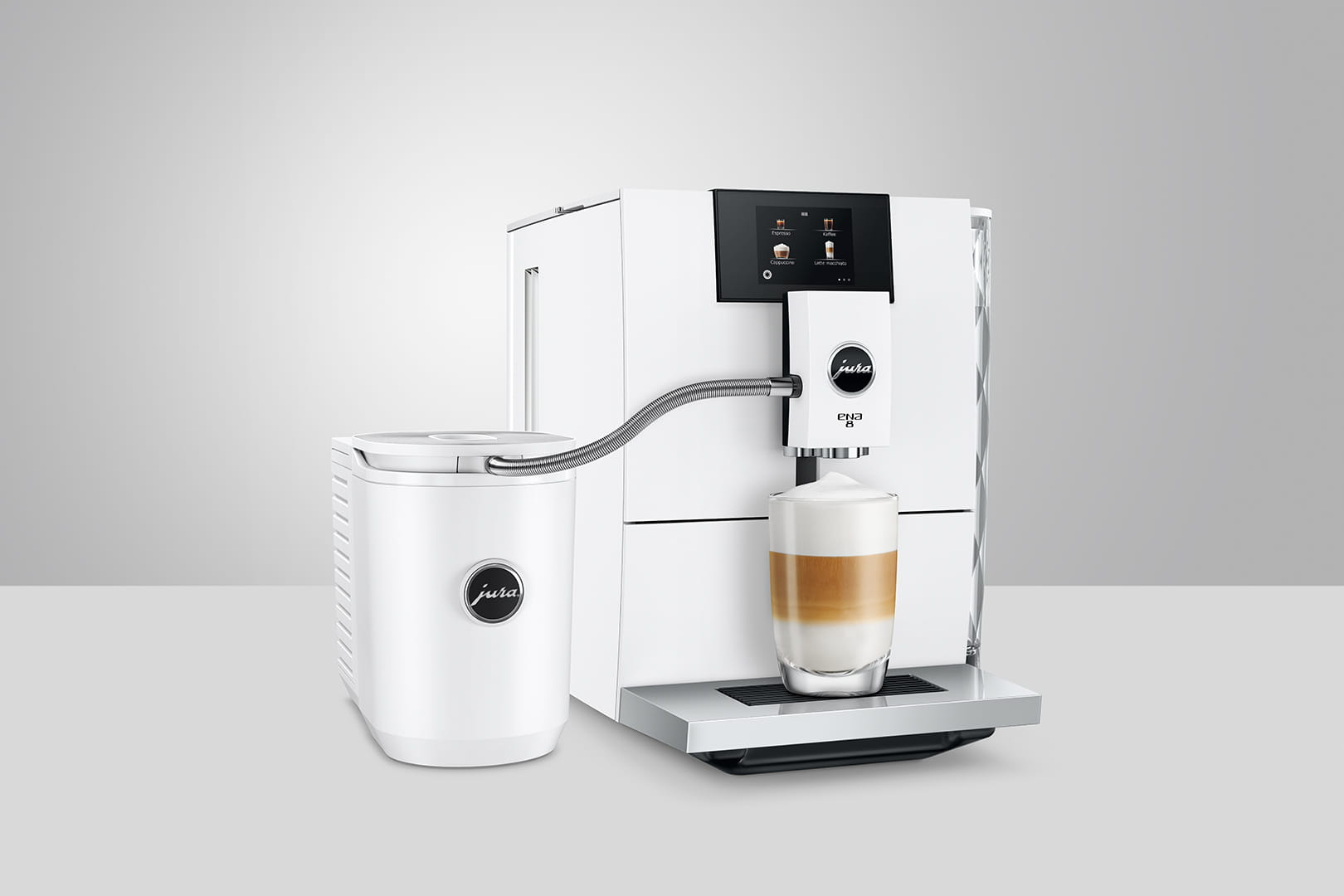 Macchina da caffè Jura bianca che fa il latte. Un bicchiere con strati di caffè e schiuma di latte è davanti.