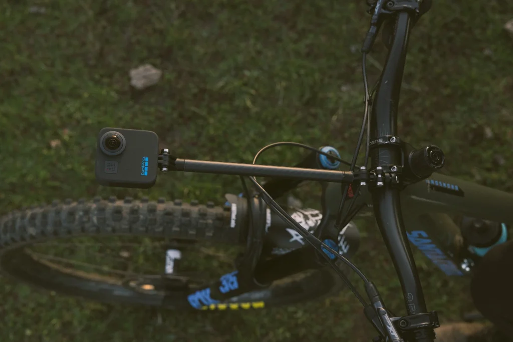 Eine GoPro-Kamera ist an einem Mountainbike montiert, vor einem grasbewachsenen Hintergrund.