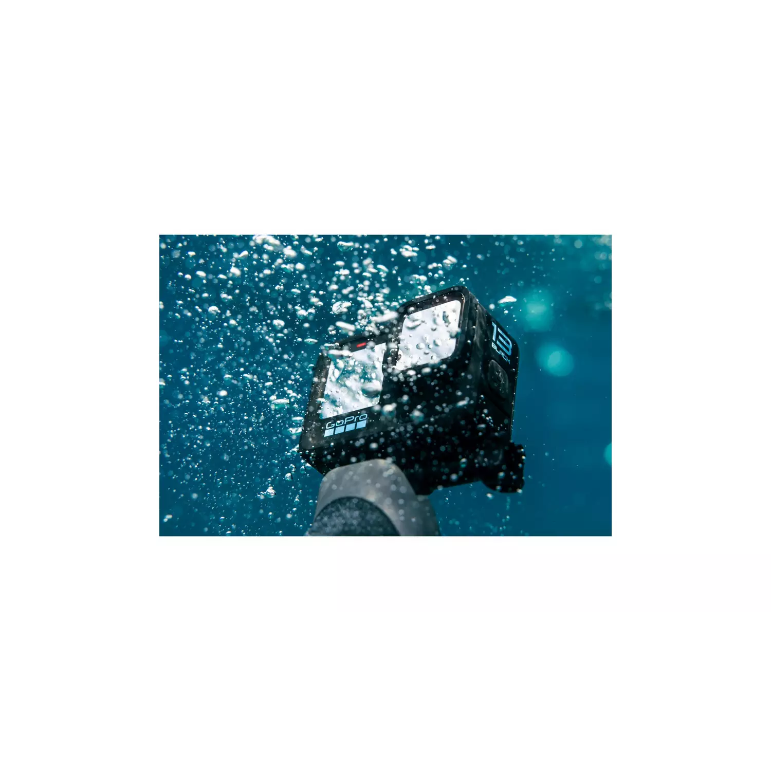 Een GoPro-camera onder water. Bellen omringen de camera, een hand houdt hem vast tegen een blauwe achtergrond.