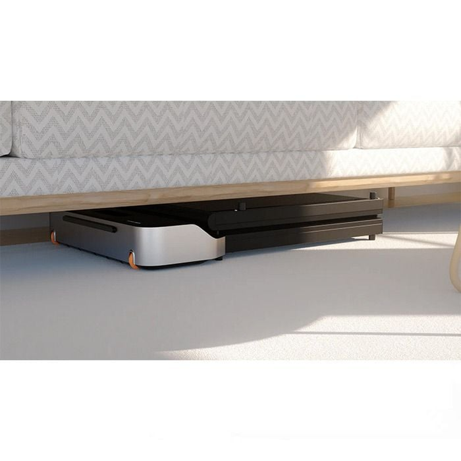 A black and silver treadmill is under a light-colored sofa. The floor is white. The treadmill has orange wheels.