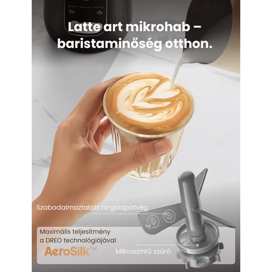 Egy kéz tart egy pohár latte art-tal. Tejet öntenek a pohárba. Egy habosító eszköz található a jobb alsó sarokban.