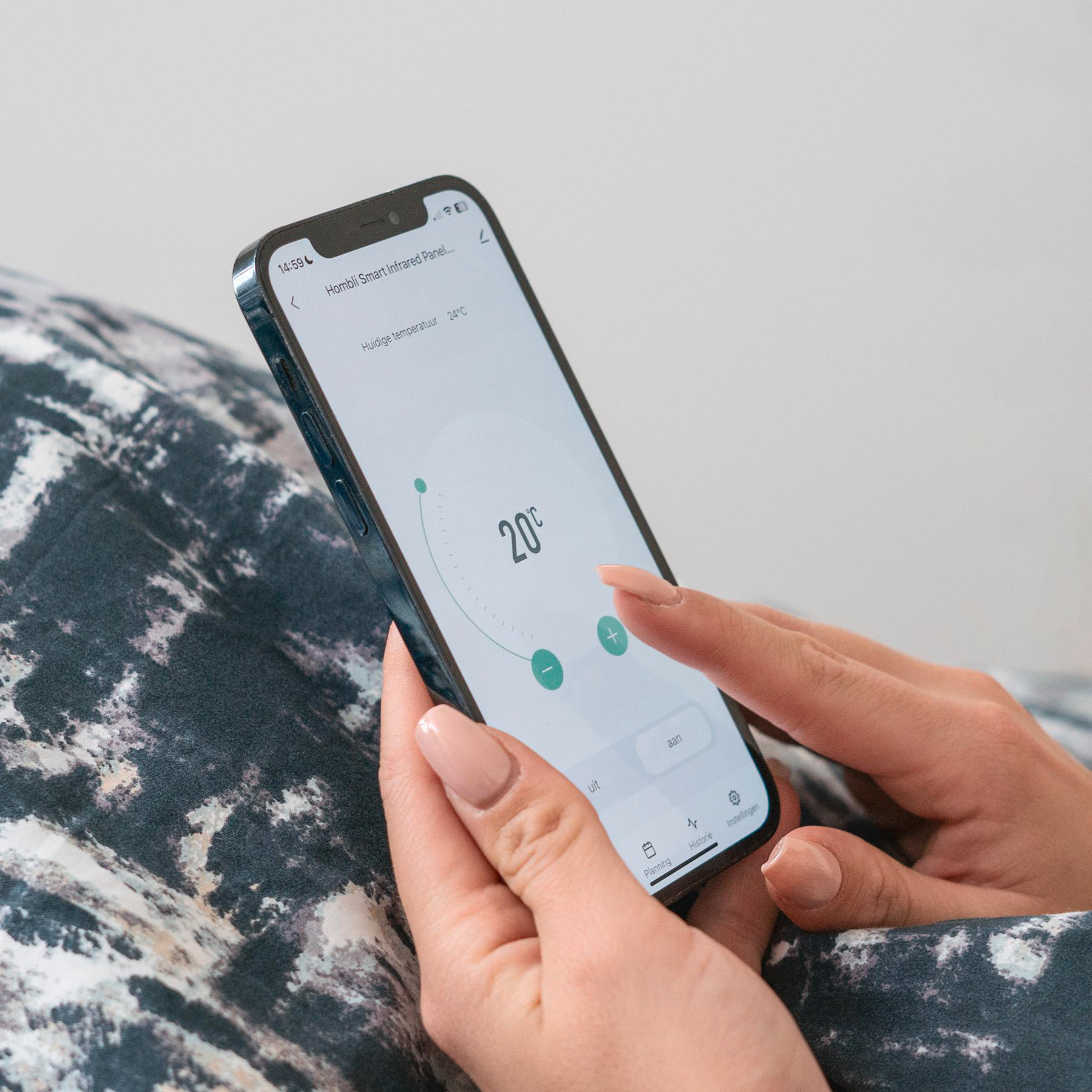 Eine Person hält ein Telefon mit einer Smart-Home-Oberfläche. Das Telefon zeigt 20°C Temperatur.