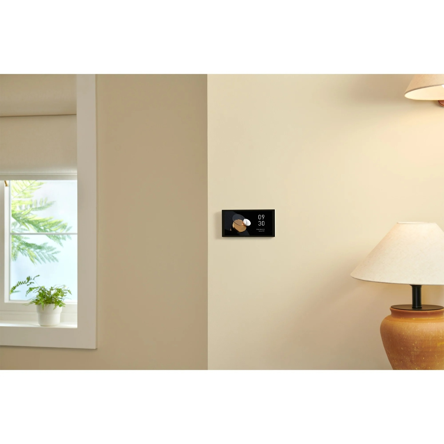 A wall with a smart home display showing time. A window with a plant and a lamp are also visible.
