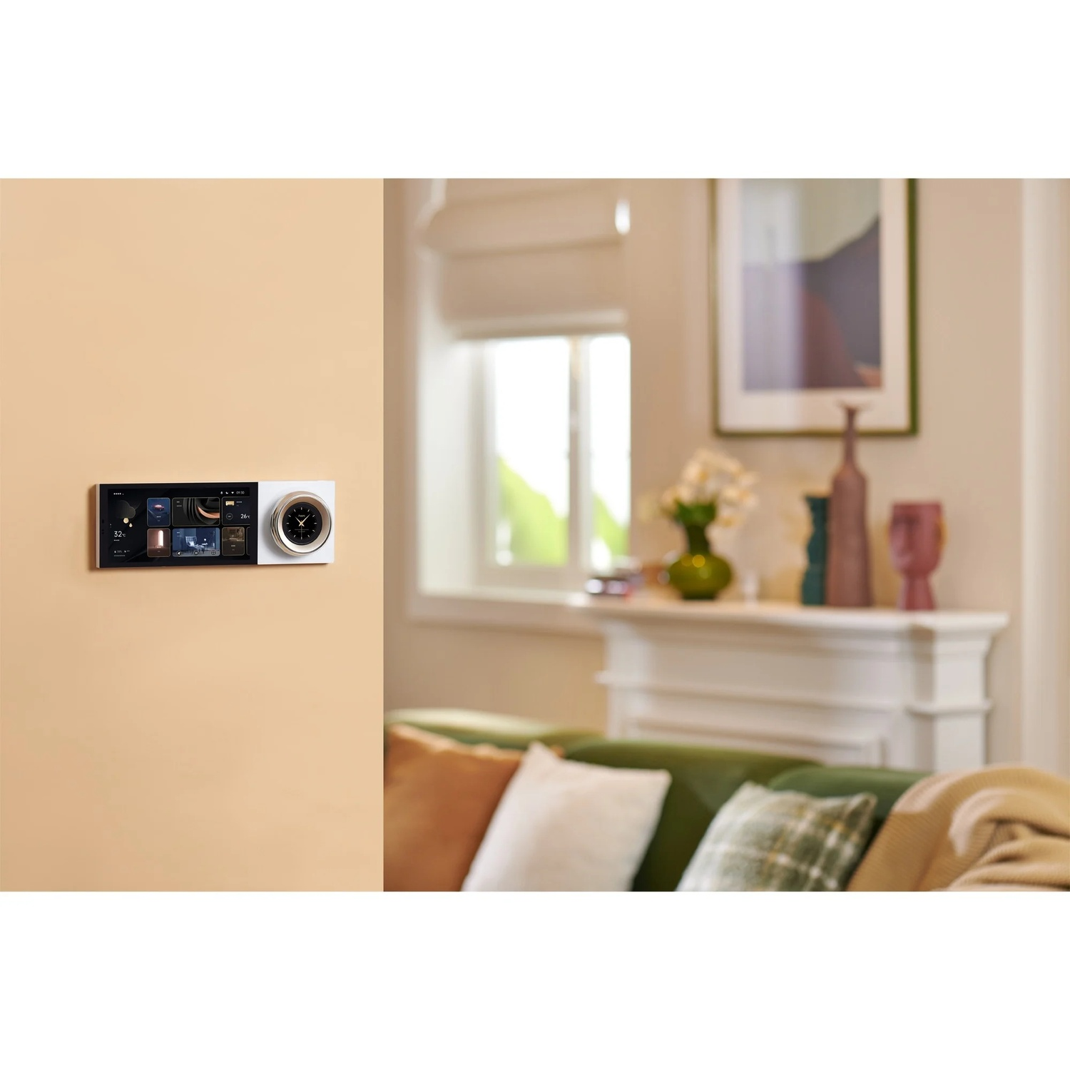 A wall-mounted control panel with a clock and screen. A green sofa, white fireplace, and window are in the background.