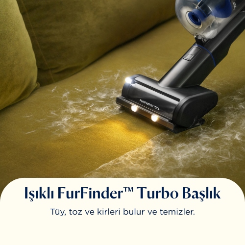 Bir elektrik süpürgesi başlığı, evcil hayvan tüyleriyle kaplı sarımsı bir kanepenin temizliğini yapıyor. Işıklar temizleme alanını aydınlatıyor.
