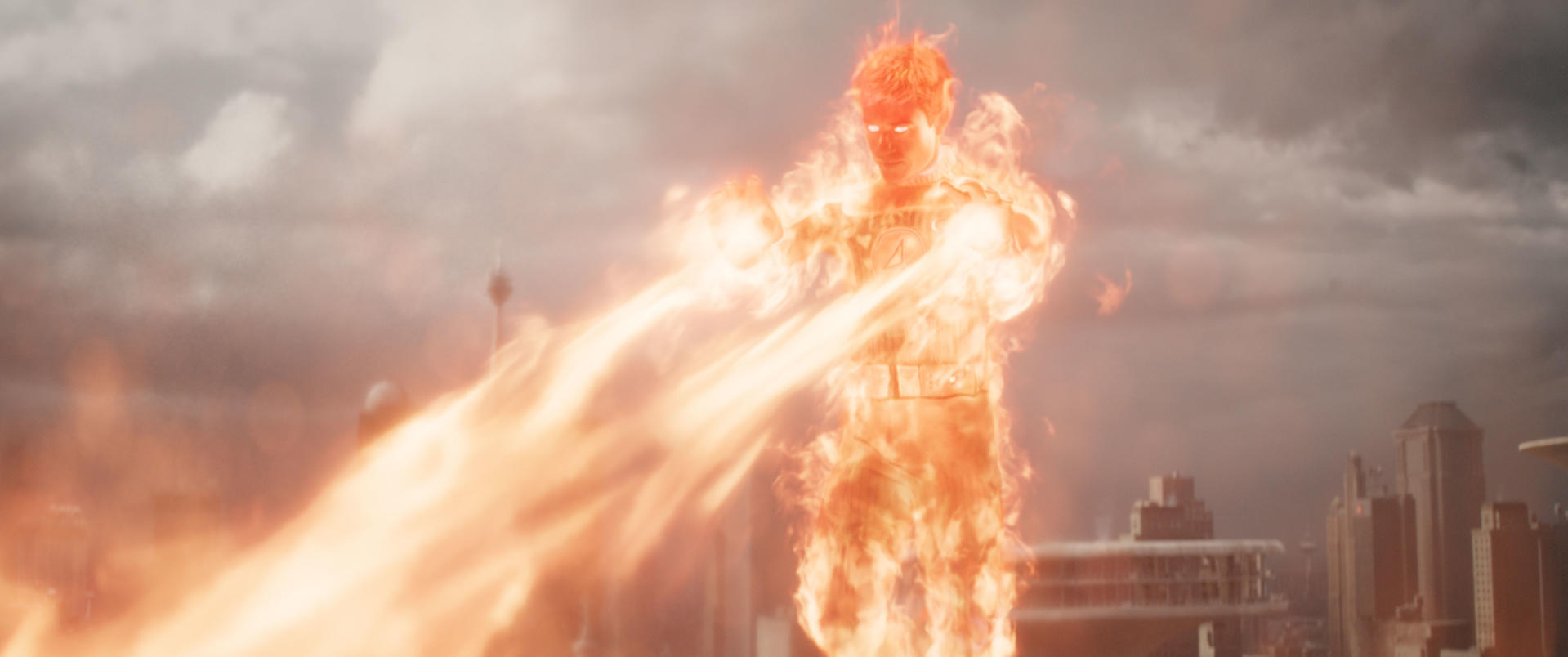 Human Torch, in Flammen, schießt Feuer nach links. Gebäude und bewölkter Himmel im Hintergrund. Das Fantastic Four-Logo ist sichtbar.