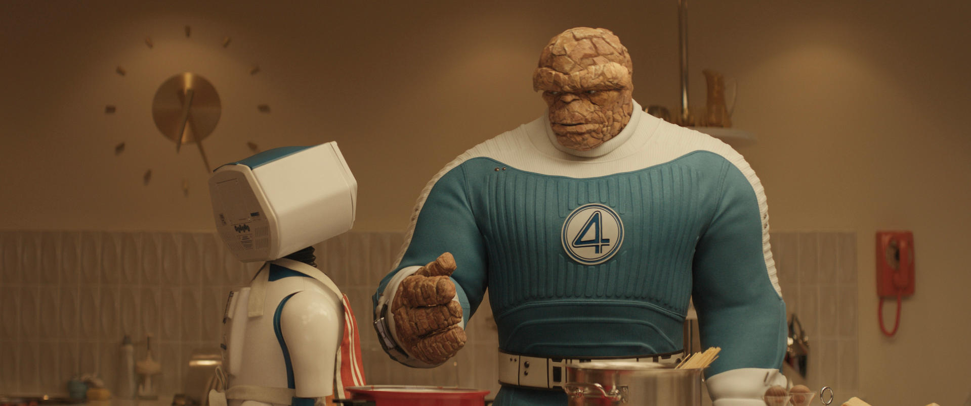Das Ding von Fantastic Four in einer Küche mit einem Roboter. Das Ding deutet auf einen Topf mit Nudeln. Eine Uhr hängt an der Wand.