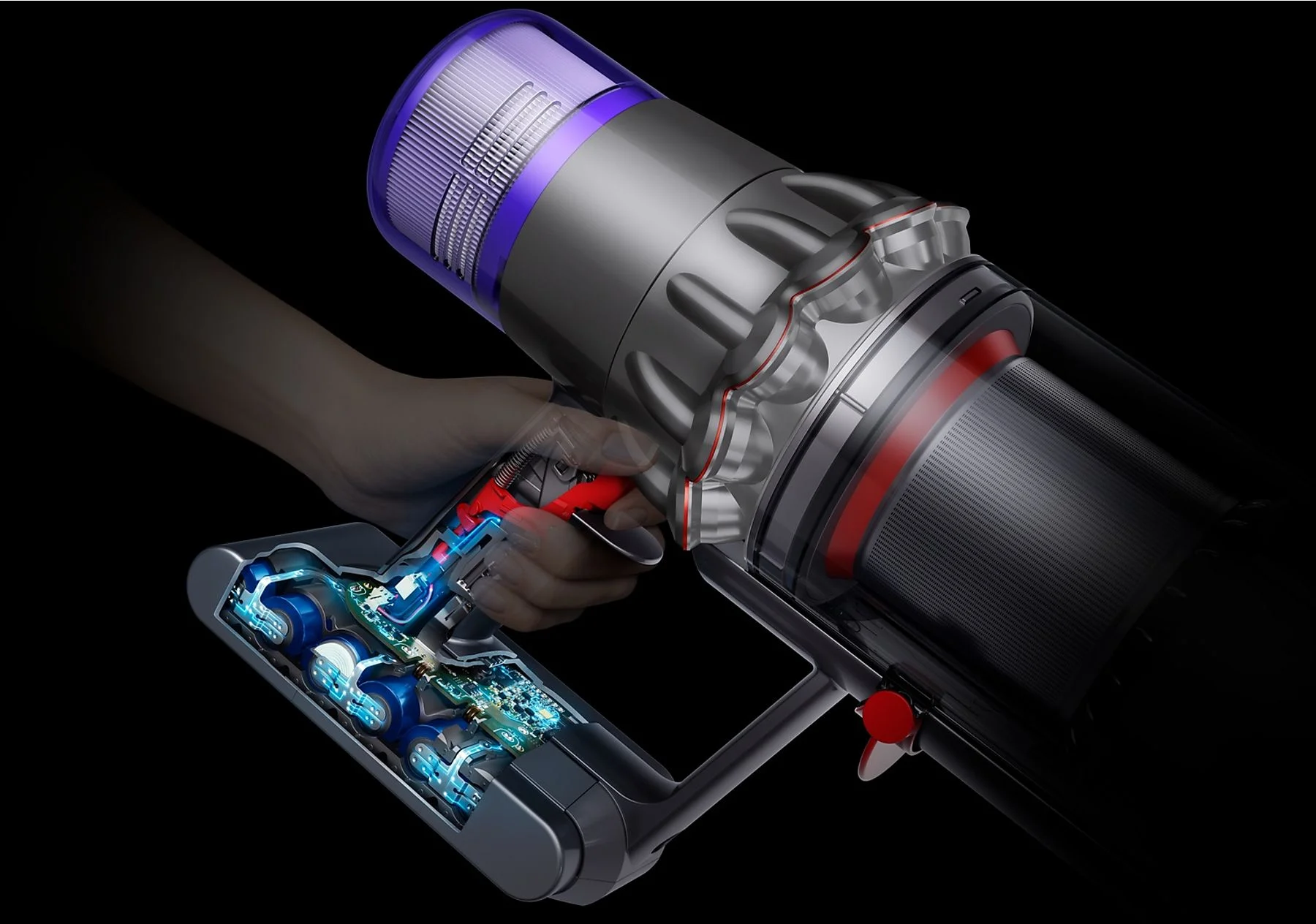 Ein Dyson-Staubsauger wird von einer Hand gehalten. Das Gerät ist grau und rot, mit einem transparenten Bereich, der Innenteile zeigt.
