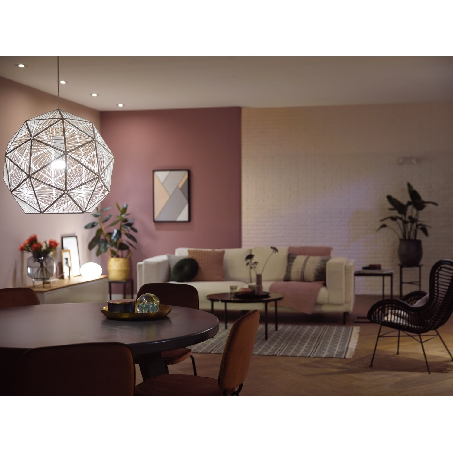 Soggiorno moderno con tavolo rotondo, divano e lampada decorativa. Piante e opere d'arte contribuiscono all'atmosfera accogliente.