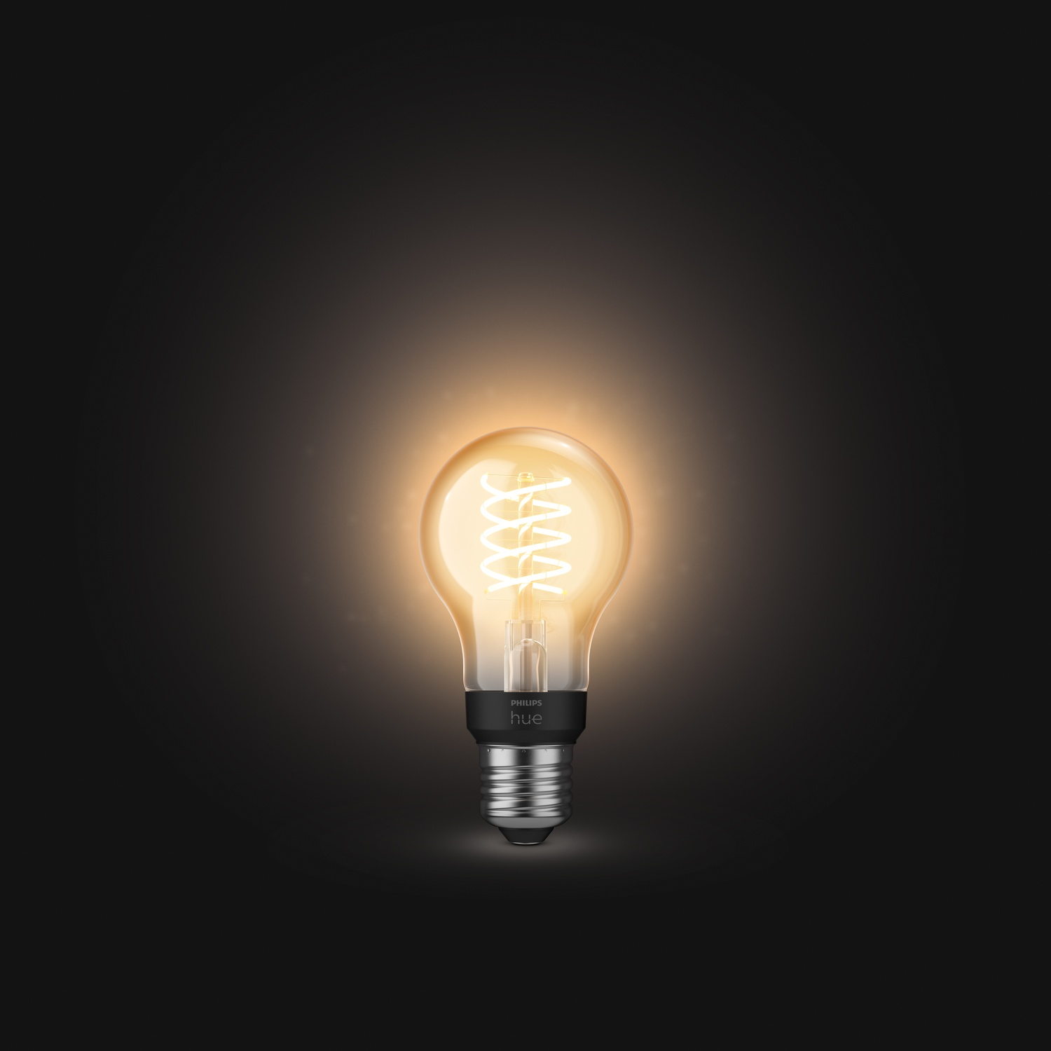 Una lampadina Philips Hue accesa su sfondo scuro. La lampadina è di colore giallo incandescente. La base è grigia e nera.