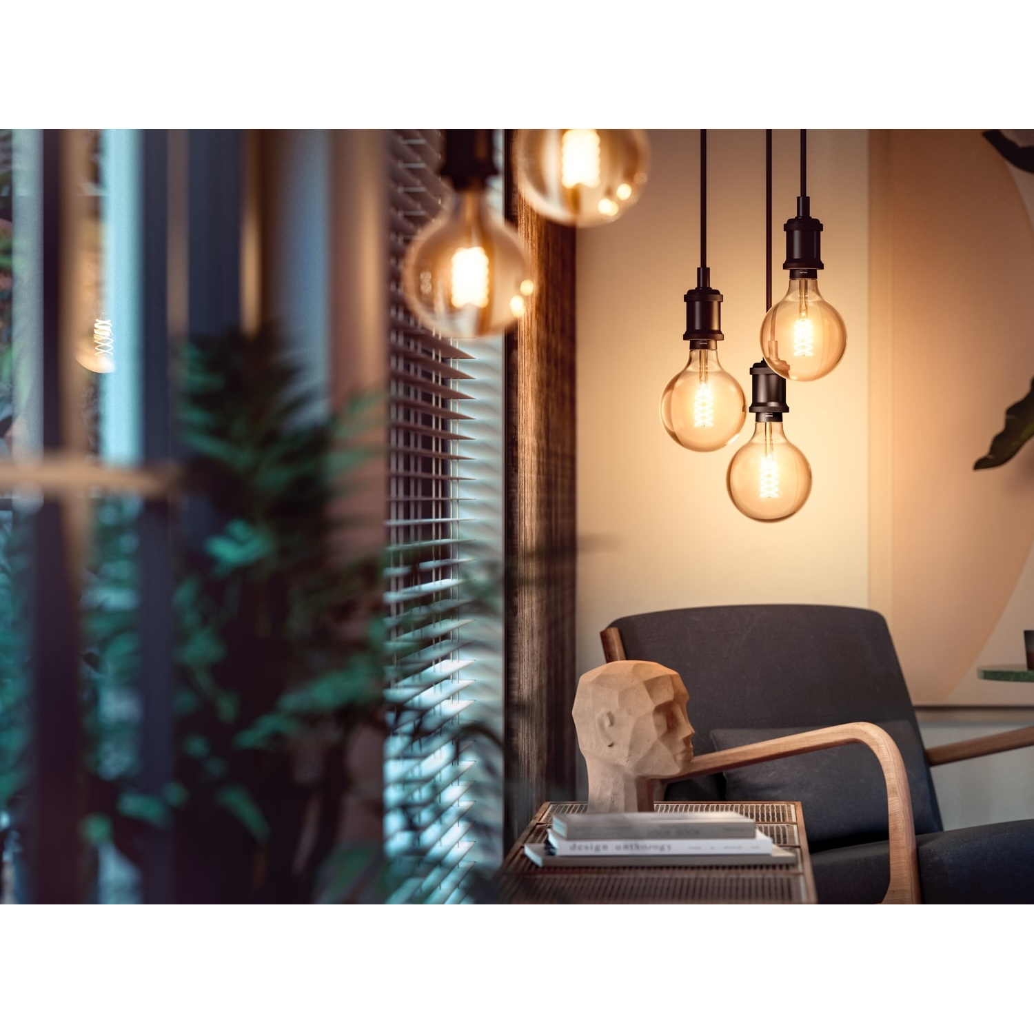 Lampadine dai toni caldi appese al soffitto. Una scultura di testa in legno è su un tavolo vicino a una sedia. Tende sullo sfondo.