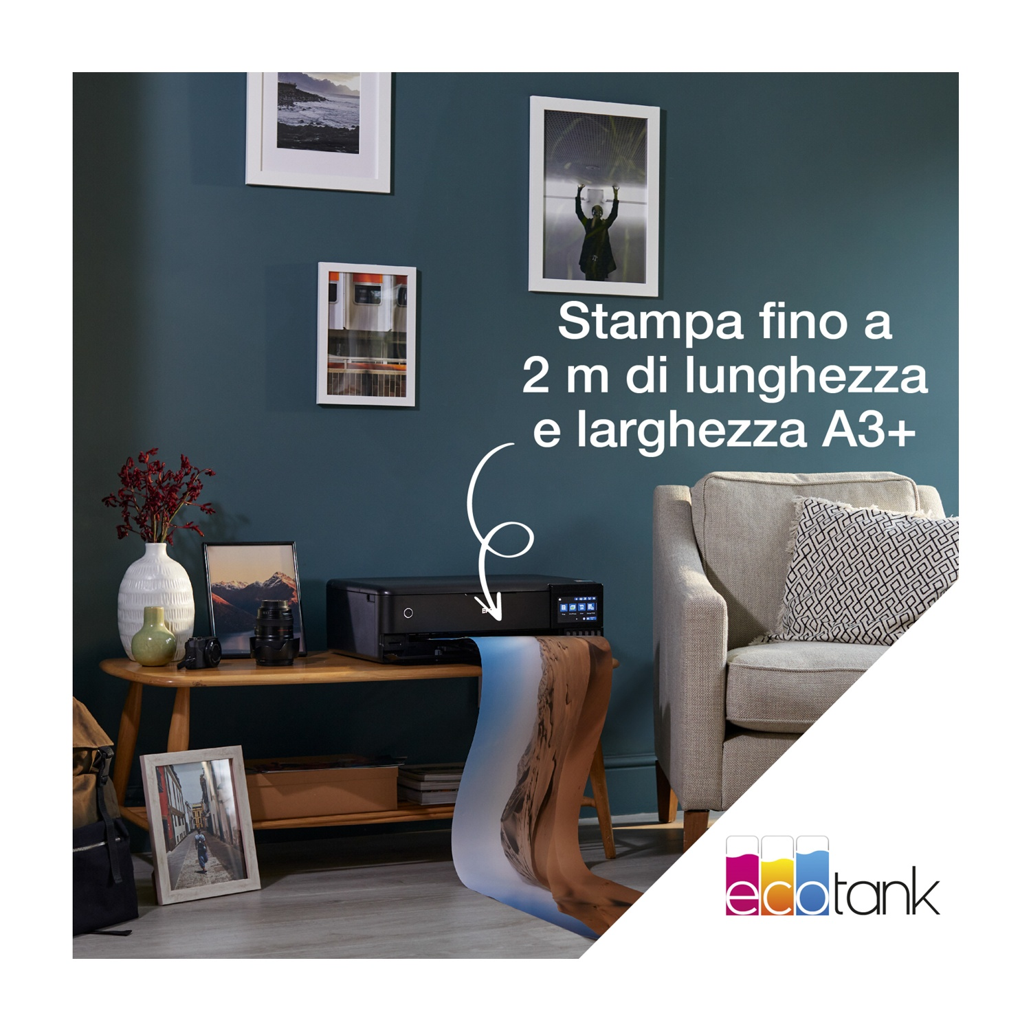 Una stanza con una stampante, quadri e un divano. Una grande stampa esce dalla stampante. Testo: Stampa fino a 2m di lunghezza e A3+ di larghezza.