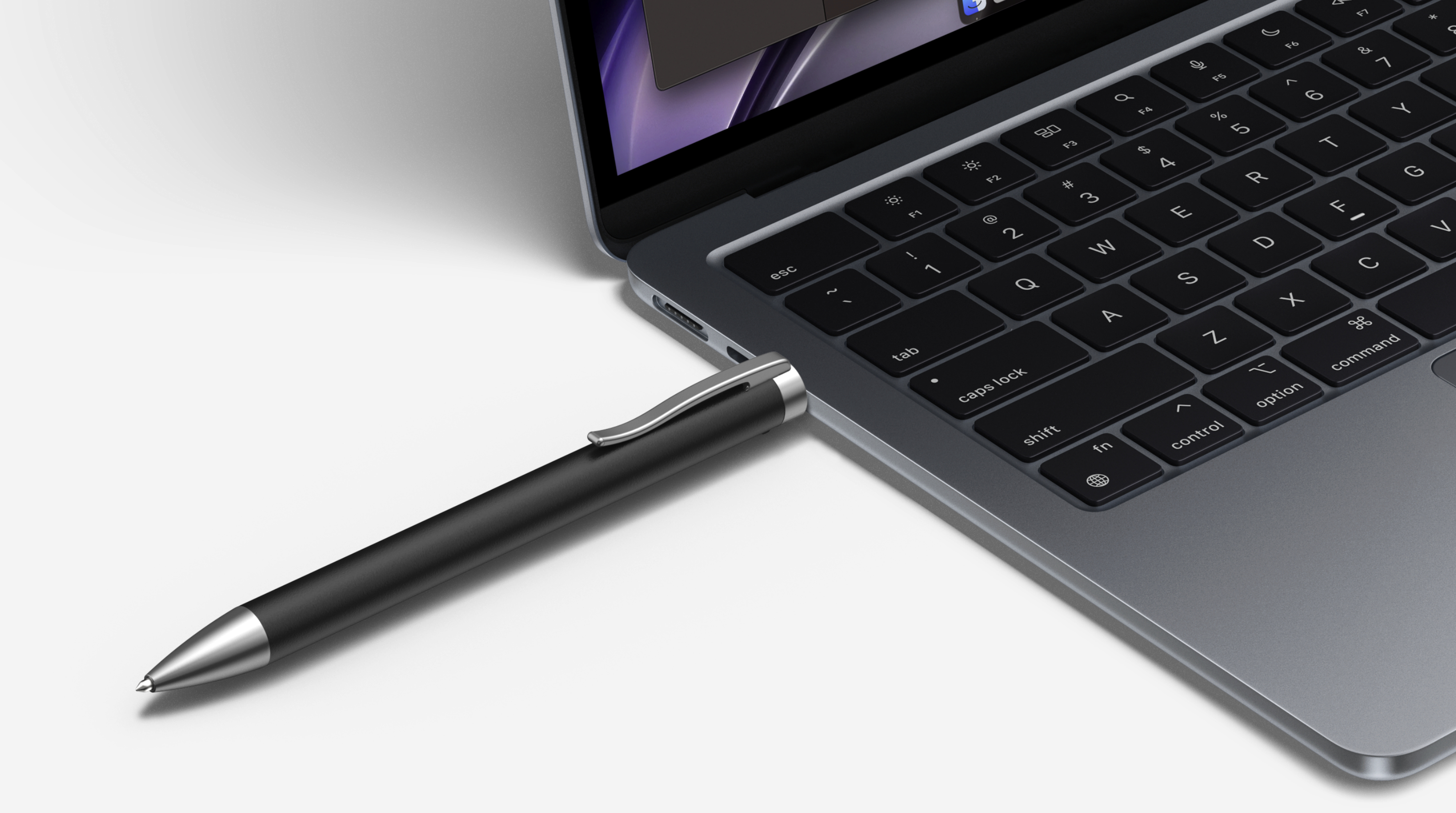 Ein schwarzer Stift ist in einen grauen Laptop eingesteckt. Die Tastatur des Laptops ist im Fokus. Weißer Untergrund im Hintergrund.
