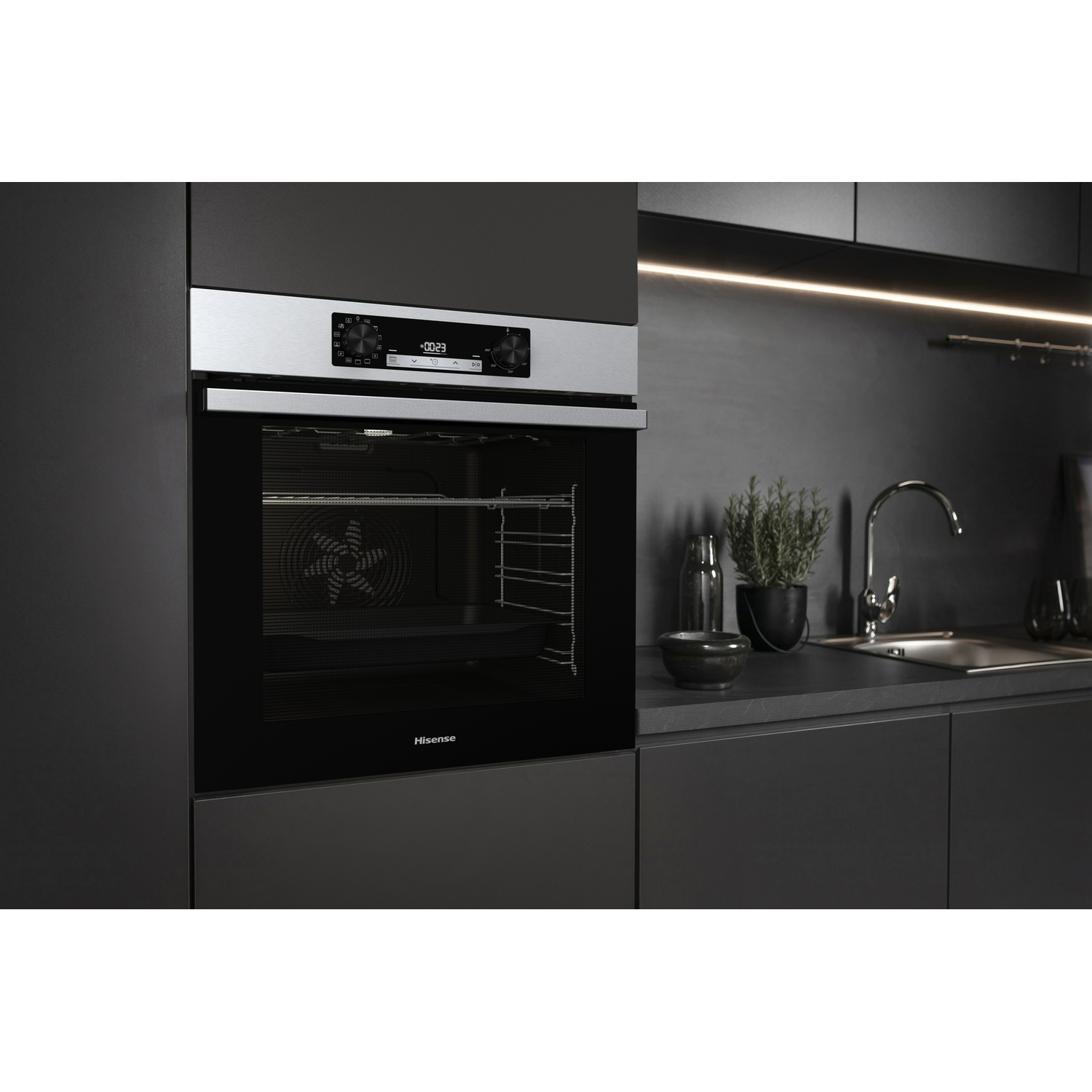 Un moderno forno nero con display digitale in una cucina. Sono visibili anche un lavandino, piante e un piano di lavoro.
