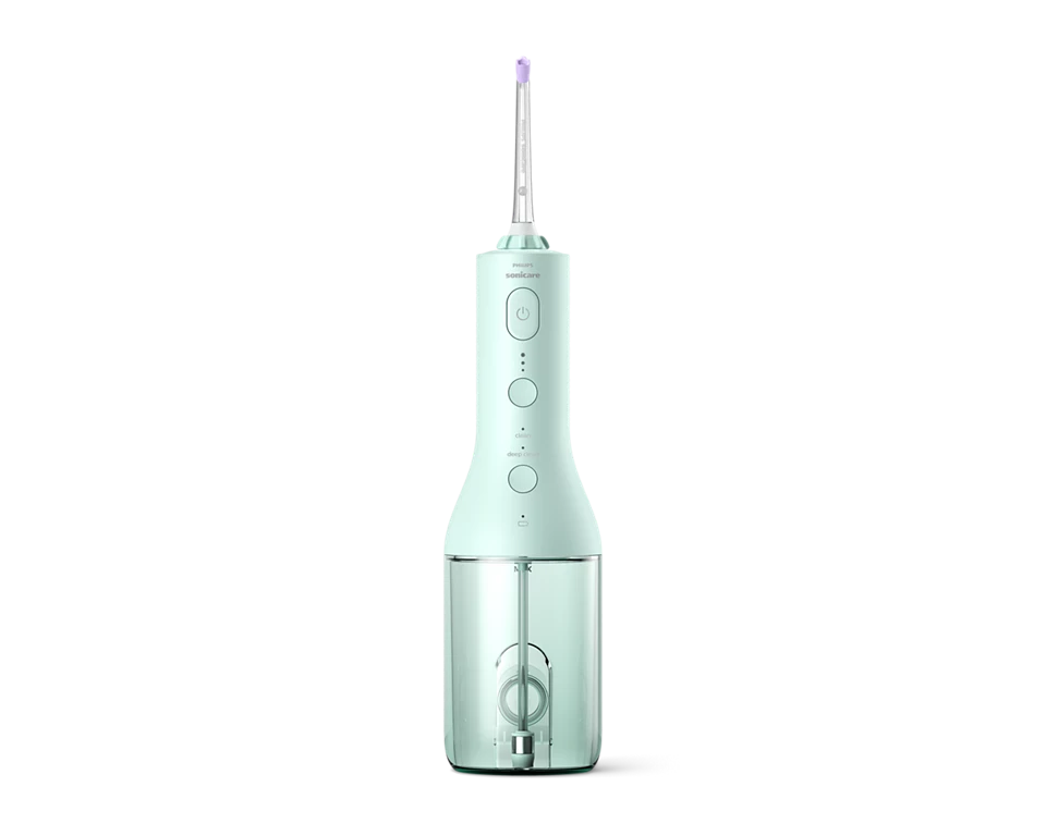 Egy mentazöld Philips Sonicare szájzuhany fekete háttéren. Átlátszó víztartállyal és vékony, lila hegyű fúvókával rendelkezik.