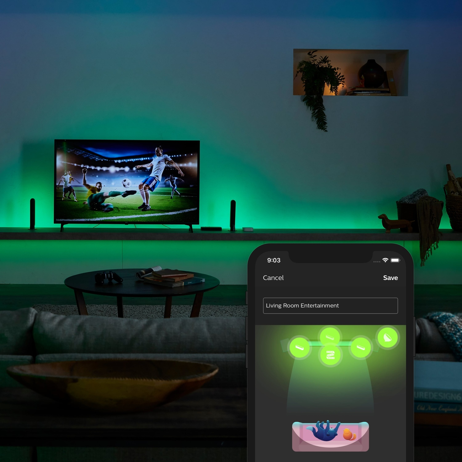 Soggiorno con TV di calcio. App per la casa intelligente controlla l'illuminazione, mostra tonalità verdi. Divano e tavolo davanti.