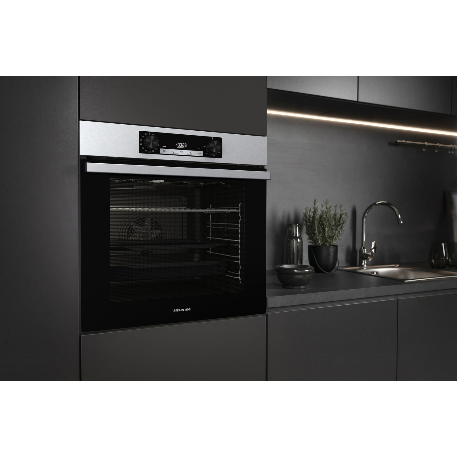 Una moderna cucina nera con forno a incasso. Piano di lavoro con lavello, pianta e altri oggetti da cucina. Il marchio del forno è Hisense.