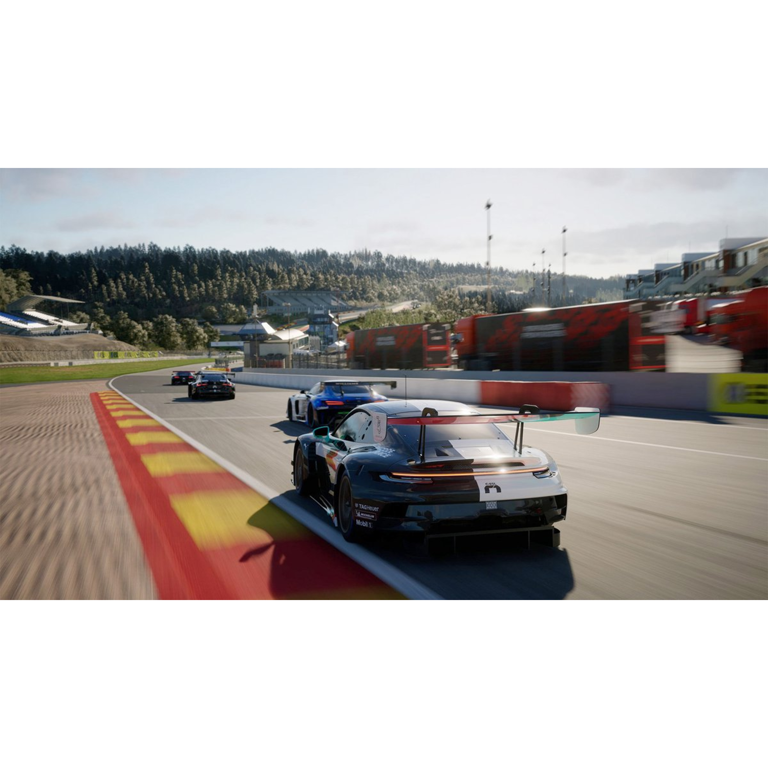 Race cars speeding on a track. A black and white car is in the foreground. Forest and buildings in the background under a cloudy sky.