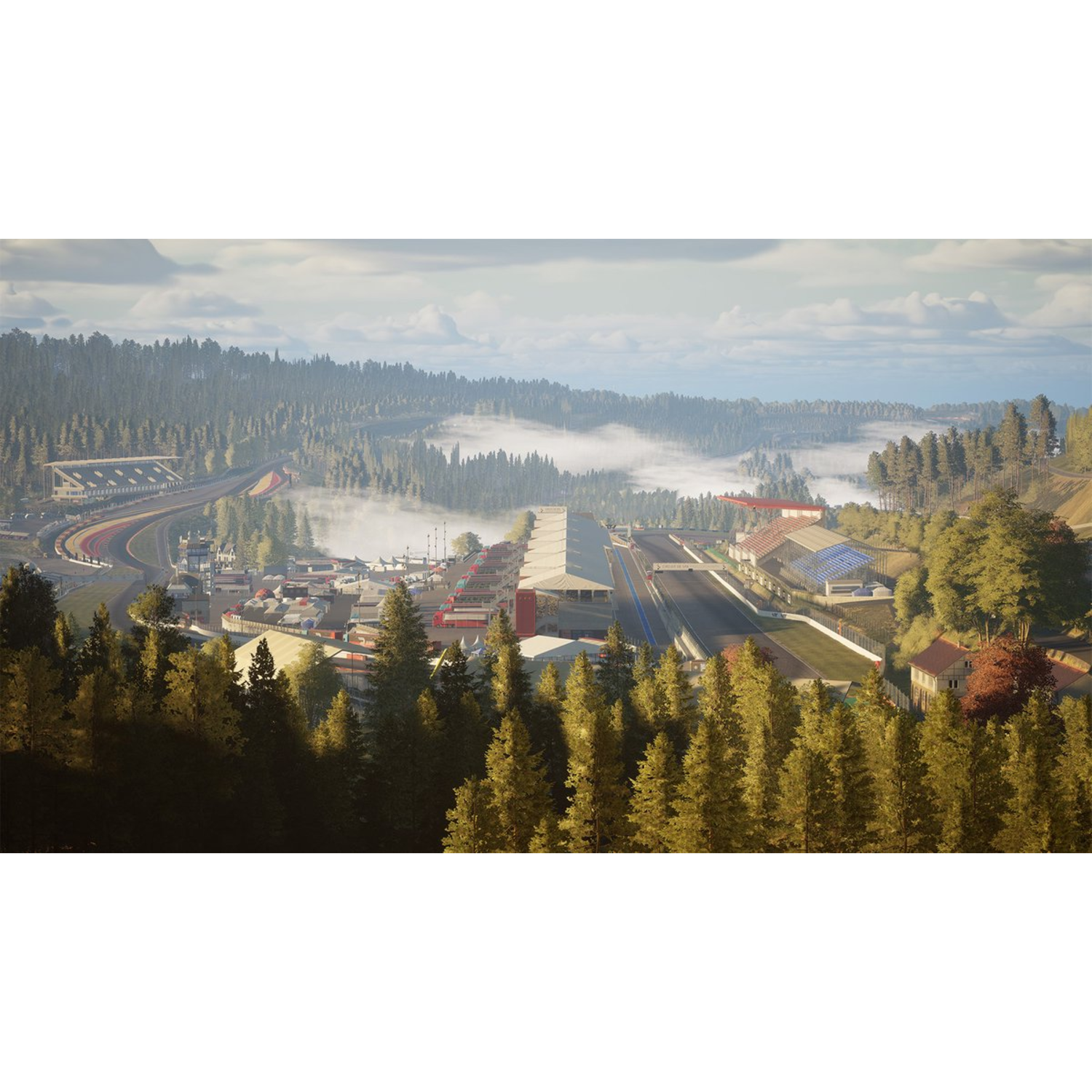 Aerial view of a race track amidst a forest. Buildings and track are visible. The sky is cloudy.