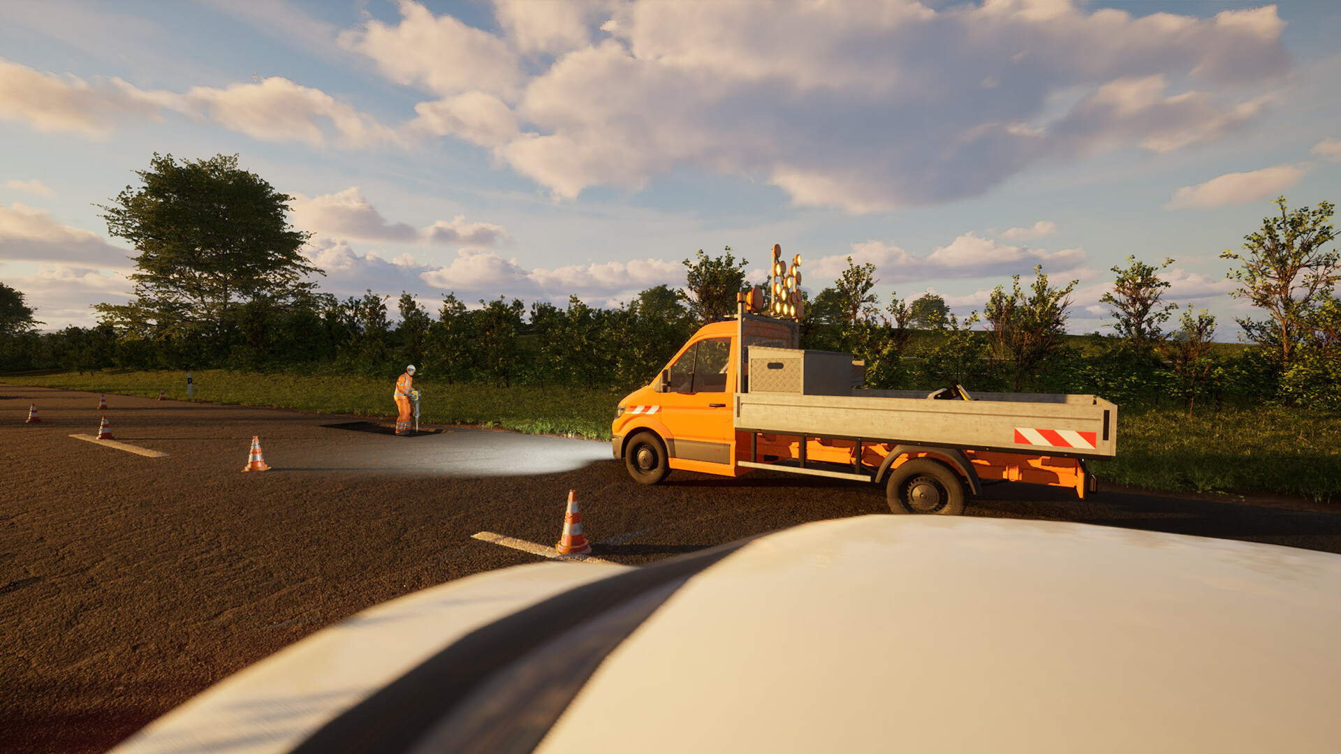 Ein orangefarbener Lkw parkt auf einer Straße. Ein Arbeiter in Orange arbeitet, mit Leitkegeln. Bäume und Himmel im Hintergrund.