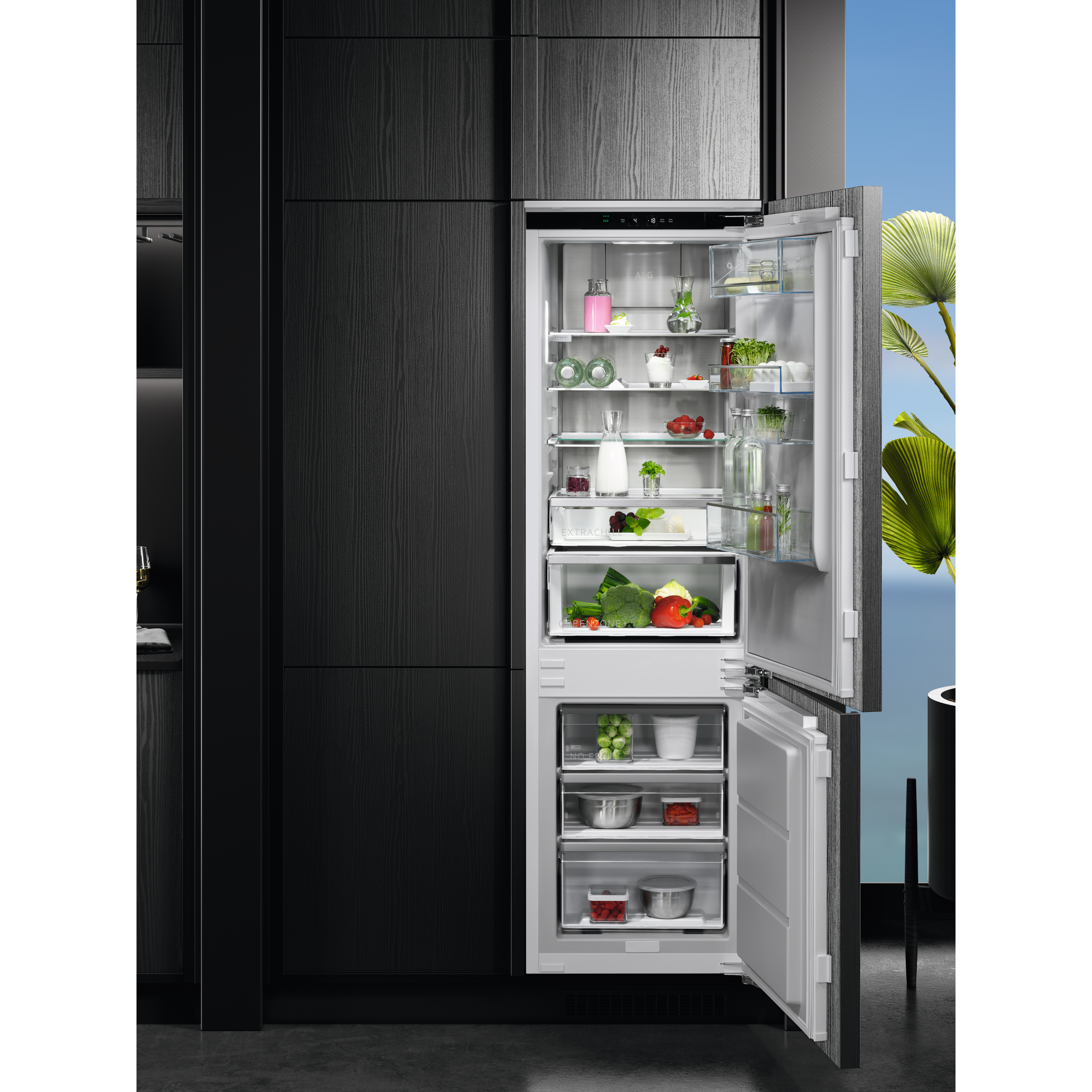 Ein offener Kühlschrank zeigt Lebensmittel. Gemüse, Obst und Getränke sind sichtbar. Der Kühlschrank ist in dunkle Holzschränke eingebaut.