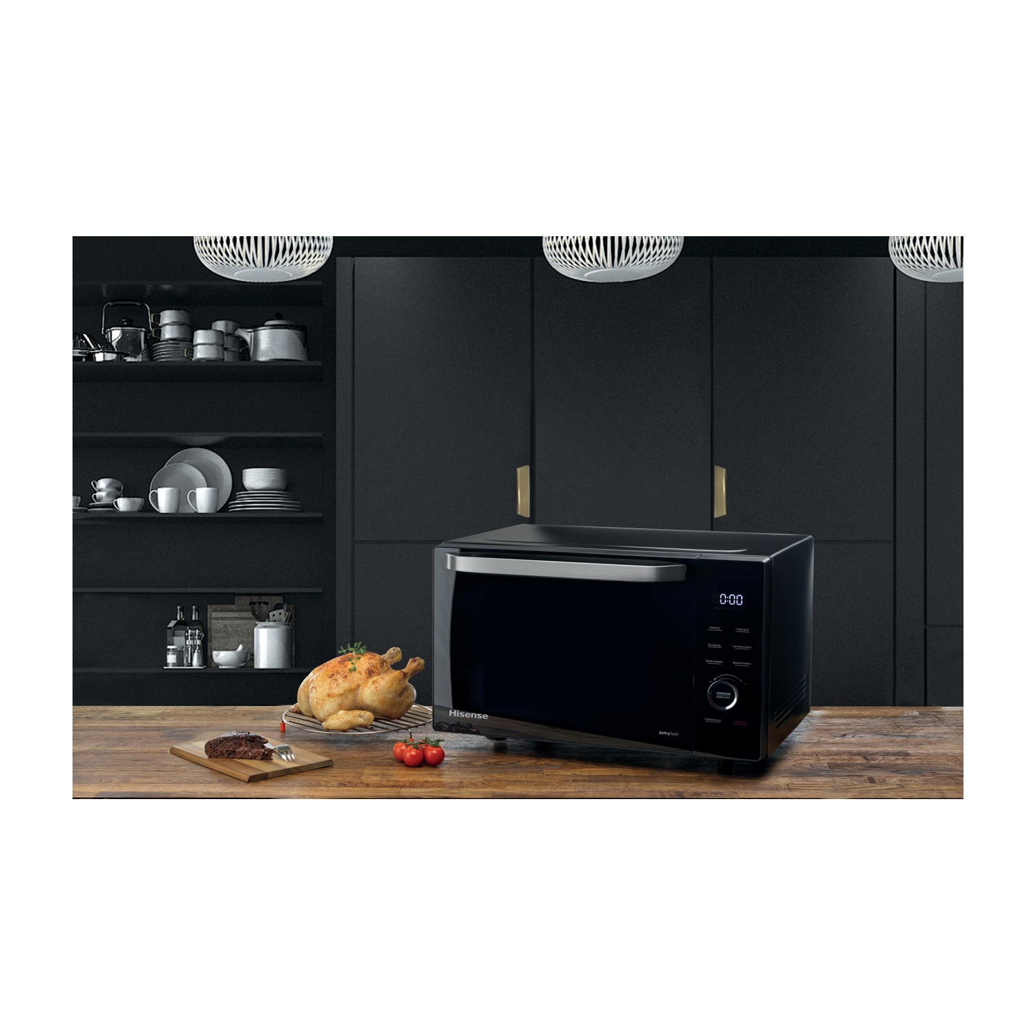 Un forno Hisense nero su un tavolo di legno con pollo arrosto, torta e pomodori. Armadi scuri sullo sfondo.