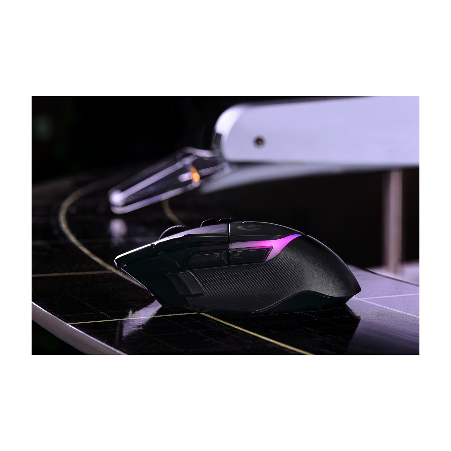 Mouse da gioco nero con illuminazione a LED rosa. È su una superficie scura con un motivo geometrico.