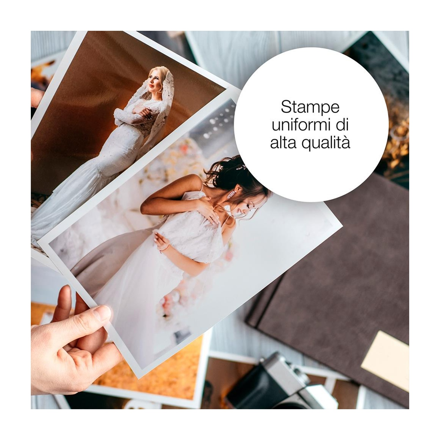 Una mano tiene foto di spose in abito da sposa. Sul tavolo altre foto, una macchina fotografica e un taccuino.