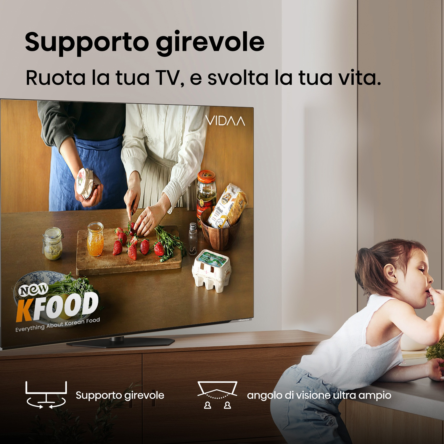 Una TV mostra cibo coreano. Due persone preparano cibo mentre un bambino mangia. La TV è su un mobile di legno. Testo: Supporto girevole.