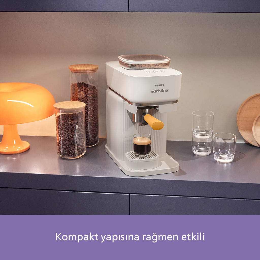 Beyaz bir Philips Baristina kahve makinesi ve bir bardak kahve. Yanında cam kavanozlarda kahve çekirdekleri.
