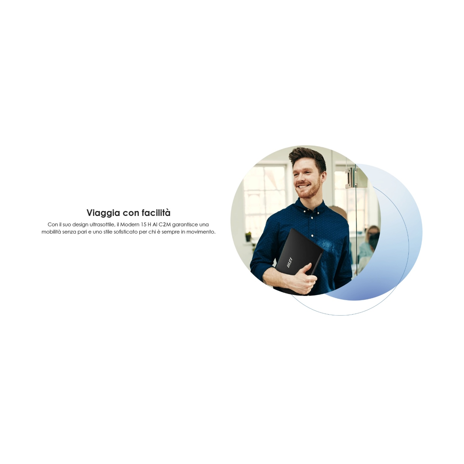 Un uomo sorridente con una camicia blu tiene un laptop nero. Si trova in un ufficio luminoso con uno sfondo sfocato.