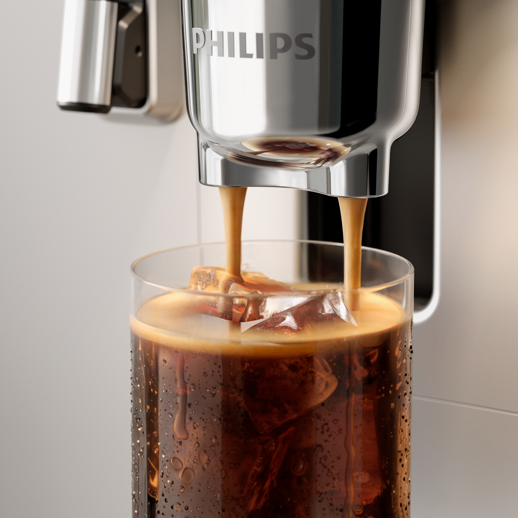 A kávé egy Philips gépből egy jégkockákkal teli pohárba ömlik. A pohár tele van kávéval és kondenzációval.