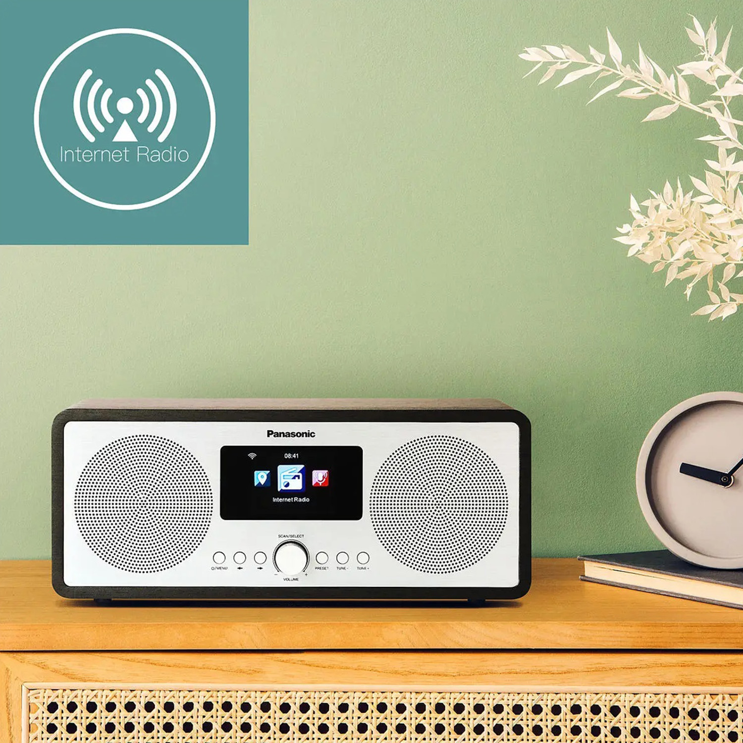 Una radio Internet è su un tavolo di legno. Un orologio e una pianta sono a destra. Un logo dice Radio Internet a sinistra.
