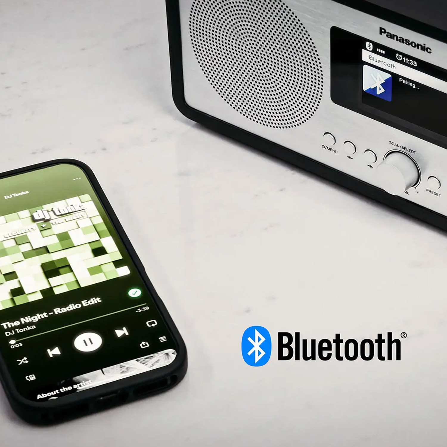 Uno smartphone mostra i controlli musicali accanto a un altoparlante Bluetooth Panasonic. Il logo Bluetooth è visibile.