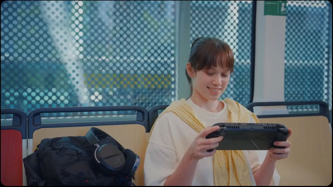 Kobieta gra na przenośnej konsoli w transporcie publicznym. Uśmiecha się. Obok niej znajduje się plecak i słuchawki.