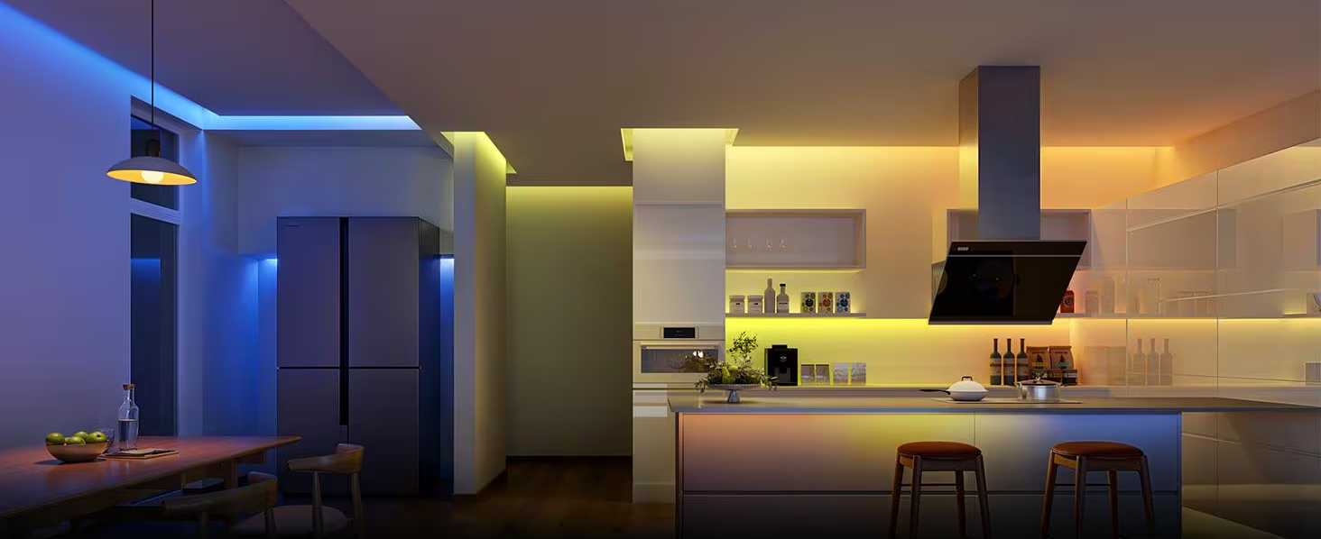 Cucina moderna con illuminazione a LED colorata. Tavolo da pranzo e frigorifero a sinistra, isola cucina con sgabelli a destra.
